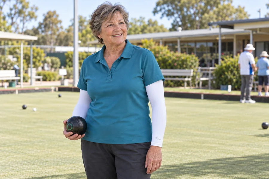 Woman in white IceRays arm sleeves holding a lawn bowl on a club green.